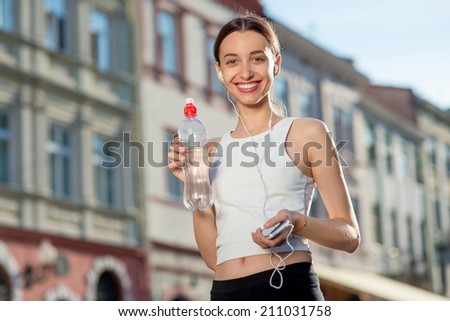 Sporty woman drinking water. Runner have a break with bottle of water. Female fitness jogger training outside for healthy lifestyle.