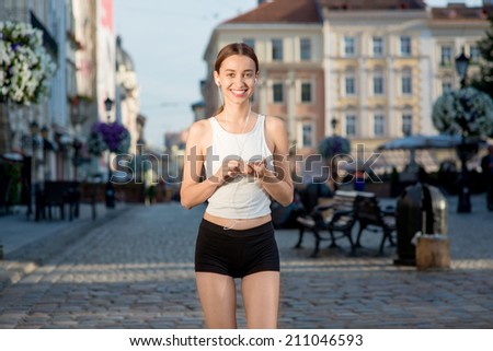 Running woman jogging to music in the city. Runner wearing earphones and armband for smart phone. Female fitness jogger training outside for healthy lifestyle.