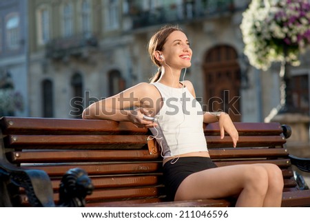 Runner have a break on the bench in the city. Female fitness jogger training outside for healthy lifestyle.