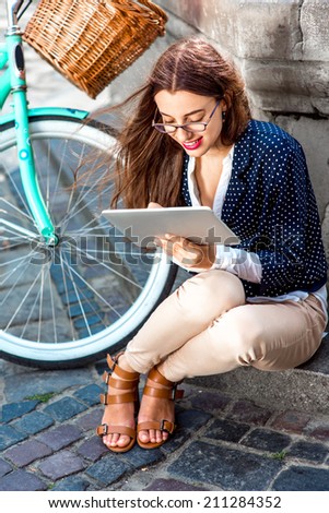 Businesswoman going to work by bicycle speaking phone in old city center background