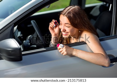 An attractive young woman drawing eyelashes in the rear view mirror while driving