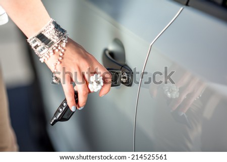 Woman opening a car using key. Close plan