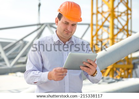 A foreman with digital tablet at the construction supervising the project.