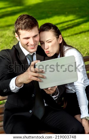 Young Business couple sitting on the bench and making selfie photo with tablets
