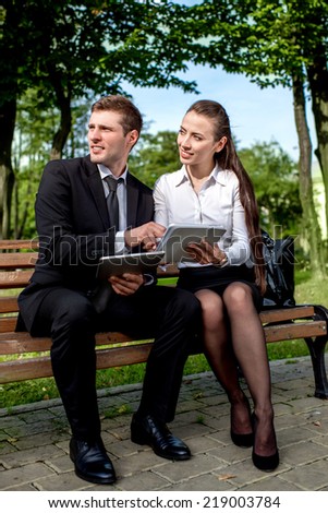 Young Business couple sitting on the bench and making selfie photo with tablets