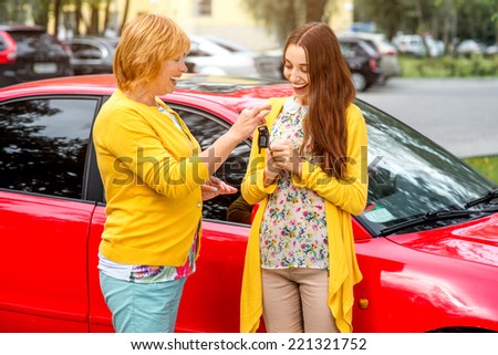Mother with her daughter near red car