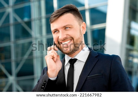 Businessman having conversation with cellphone on the contemporary building background