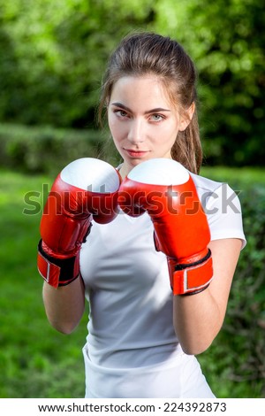 Young sports woman boxing with gloves to the camera in the park