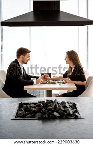 Young couple sitting and having lunch at the restaurant or home. General plane with the kitchen on the front