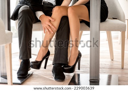 Young couple flirting with legs at the restaurant under the table
