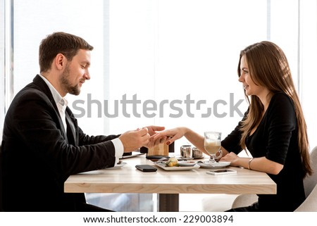 Man making proposal with the ring to his girlfriend at the restaurant. Shocked and surprised woman