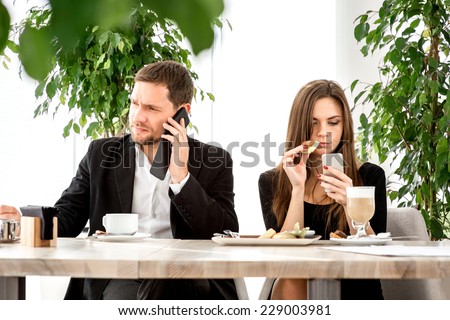 Young couple being busy using their smart phones at the restaurant
