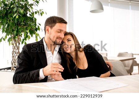 Young loving couple embracing at the restaurant and waiting for the order.