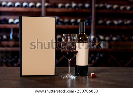 Wine bottle with glass and menu on the table at the wine cellar