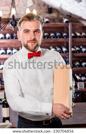 Sommelier showing wooden wine box with expensive wine in the wine cellar
