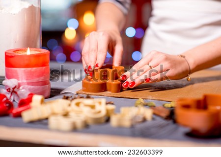 Making ginger cookie on Christmas decorated table on festive lighting background