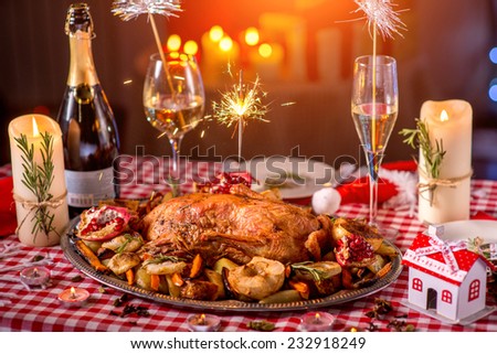 Turkey garnished with potato, apples, garnet and Bengal light on Christmas decorated table