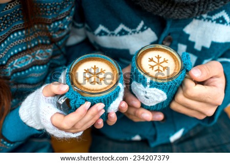 Couple holding knitted coffee cups dressed in sweater