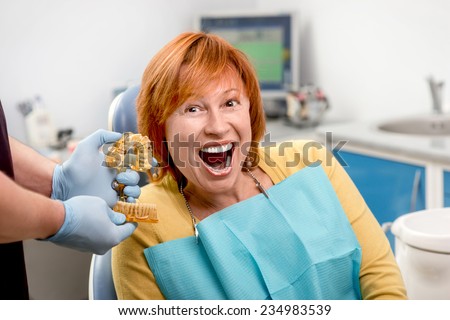 Smiling senior woman with new dental implants sitting in the dental office