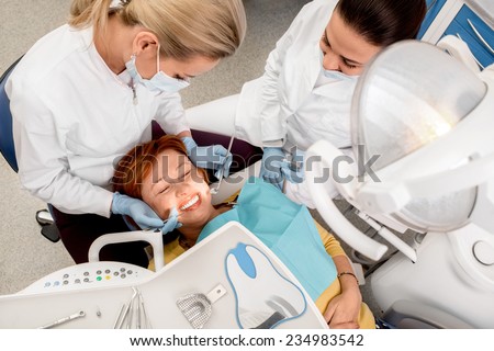 Senior woman on the operation in the dental office. Dentist with assistant examining implants teeth. Top view.