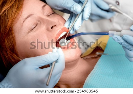 Senior woman on the operation in the dental office. Dentist with assistant examining implants teeth