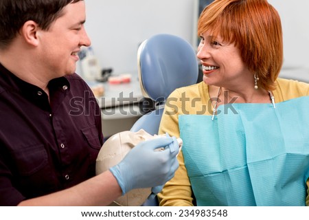 Dentist showing teeth on skull to elder woman patient in the dental office