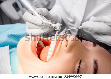 Dentist making professional teeth cleaning female young patient at the dental office. Close-up plan