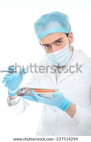 Dentist in mask with dental equipment before the operation isolated on white background
