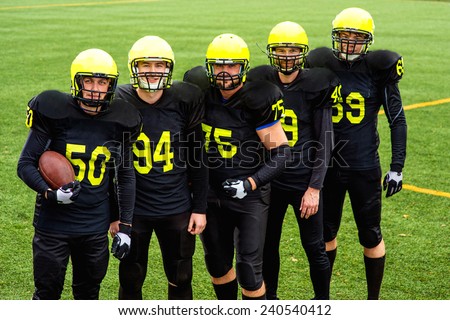 American football team in sportswear with the ball standing together on the sports ground