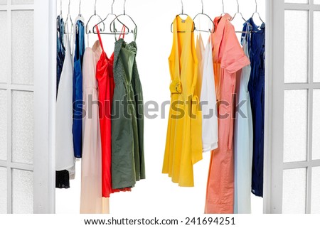 Wardrobe with colorful dresses on hangers on white background