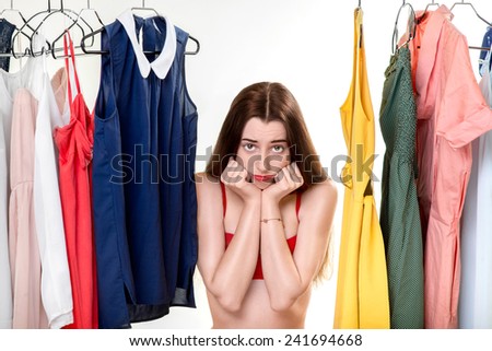 Young upset woman in underwear thinking what dress to wear in front of the clothes in wardrobe. Nothing to wear concept