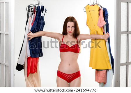 Young upset woman in underwear looking through her wardrobe. Nothing to wear concept