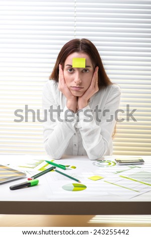 Young tired woman economist working with paper graphics, digital tablet and smart phone