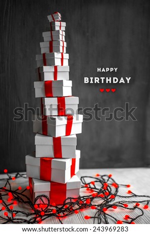A pile of gift boxes with red ribbons on wooden background with greeting text. Greeting card concept