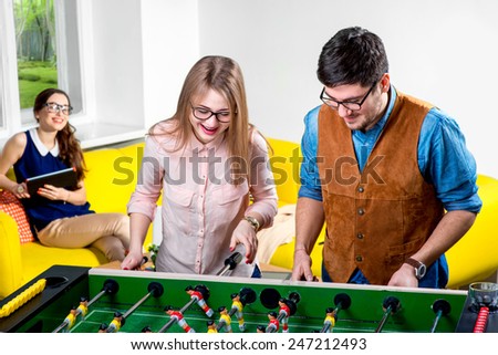 Young friends or students having fun together playing table football
