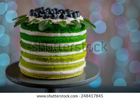 Nice sponge happy birthday cake with mascarpone and grapes on the cake stand on festive light bokeh