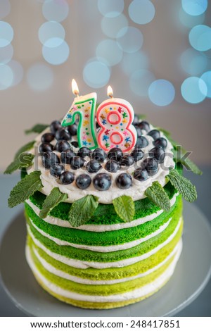 Nice sponge happy birthday cake with mascarpone and grapes on the cake stand with candles on festive light bokeh