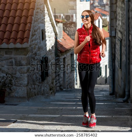 Young sporty woman running in the old city street in the morning