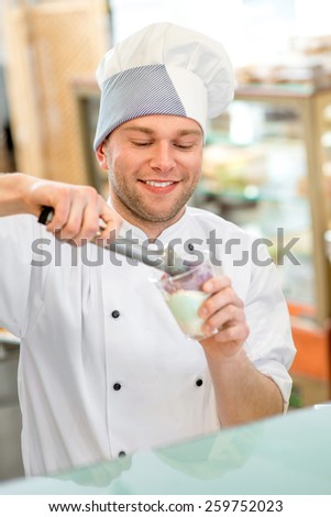 Confectioner putting ice cream to the cup for takeaway in the store