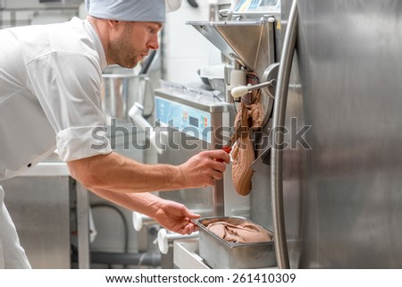 Handsome confectioner in chef uniform producing ice cream with ice cream machine