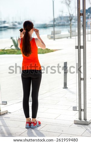 Young sport woman with phone waiting at the bus station