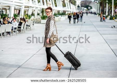 Young woman with travel bag and phone walking at the promenade in Split cty in Croatia