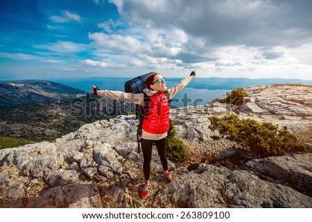 Young woman mountain climber with backpack and sleeping back hiking on the rocky mountain
