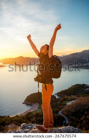 Photographer with professional photo camera and backpack on the top of the mountain on the beautiful sunset.