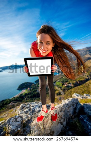Sports woman showing digital tablet with empty dcreen on the mountain. Hiking or sports application concept