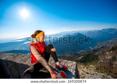 Sport woman resting after jogging on the mountain road on the sunset with beautiful landscape view