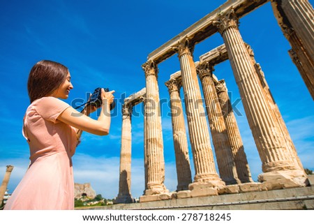 Young and smiling woman photographer taking picture with professional camera of Zeus temple in Acropolis