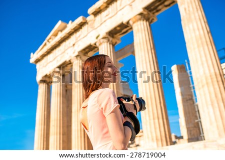 Young and smiling woman photographer taking picture with professional camera of Parthenon temple in Acropolis