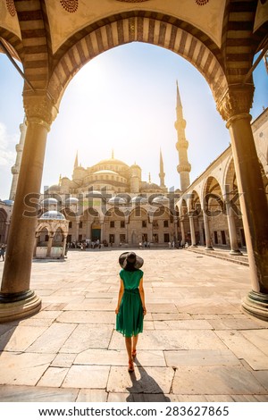 Young woman traveler in the green dress and hat walking to the Blue Mosque in Istanbul