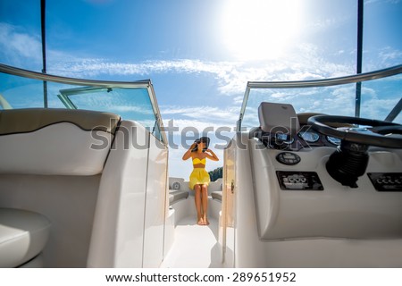 Young and pretty woman in yellow swimsuit relaxing on the yacht floating in the sea. Luxury summer recreation concept
